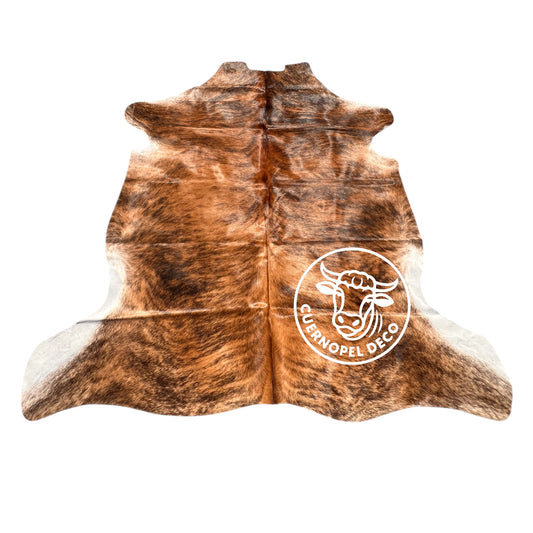 Brindle cowhide rug with rich natural tones of dark brown, black, and caramel, displayed on a wooden floor in a rustic interior. Each hide is one-of-a-kind, showcasing organic patterns and textures that bring warmth, authenticity, and character to any space. Perfect for country homes, modern rustic decor, or as a statement piece in natural interiors.
